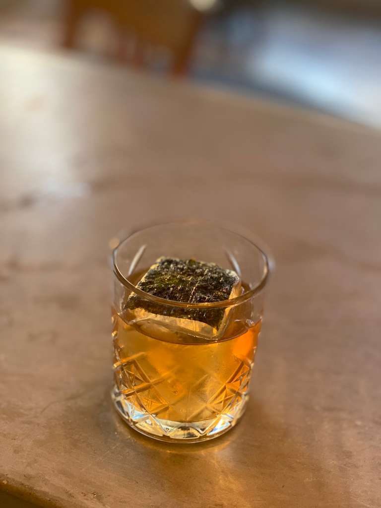 Amber spirit-forward cocktail over a large clear ice cube