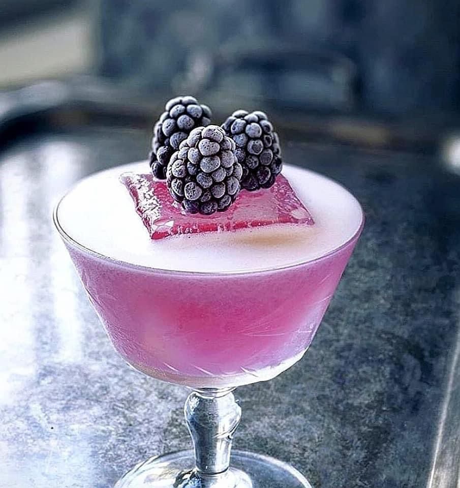 Elegant coupe cocktail in deep berry tones, crowned with sugared blackberries