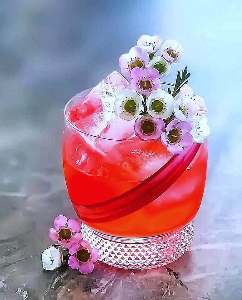 Bright red cocktail garnished with fresh flowers